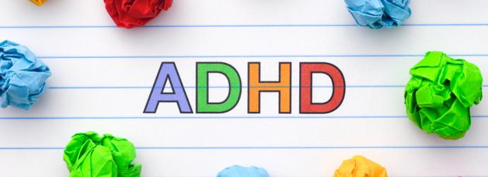 ADHD written on a piece of paper with scrunched up colourful paper around it