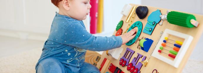An image of an early years child playing with a colourful wooden toy
