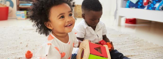 two children playing on with a toy on the floor