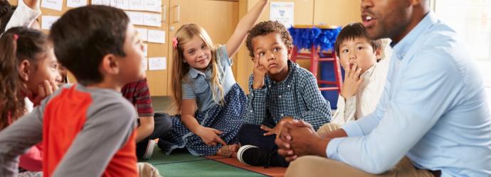 image_shows_male_teacher_with_children_sitting_on_the_floor