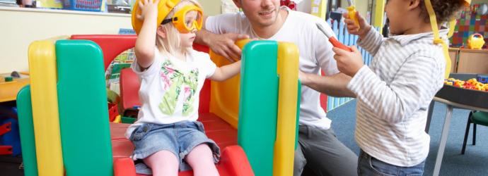 teacher playing with two children on a slide