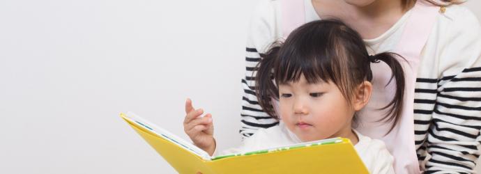 young child reading with their parent