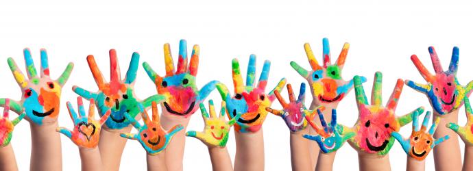 Children's hands waving with colourful smiley faces painted on them