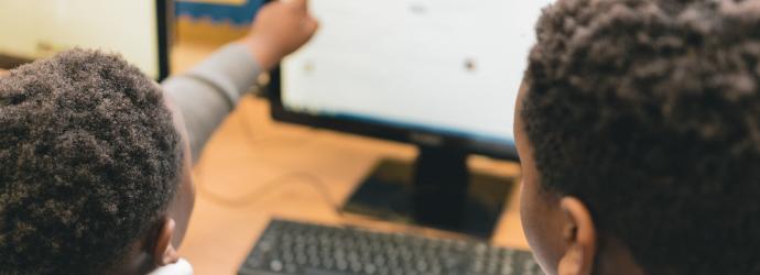 Image shows two pupils using a computer, with one pointing at the screen