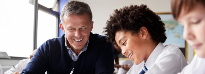 male teacher supporting a pupil in classroom