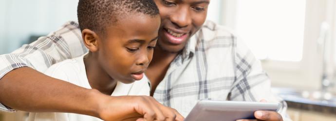 young boy looking at an tablet with an older male who could be the father