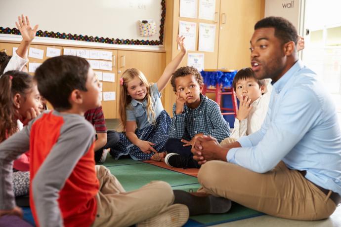 image_shows_male_teacher_with_children_sitting_on_the_floor