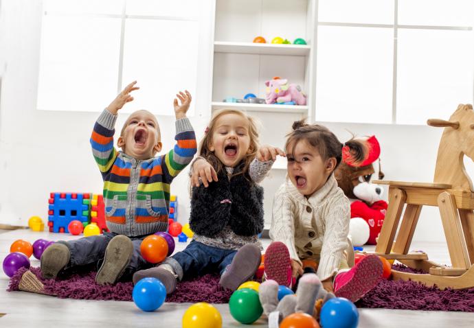 Three early years children playing with plastic balls