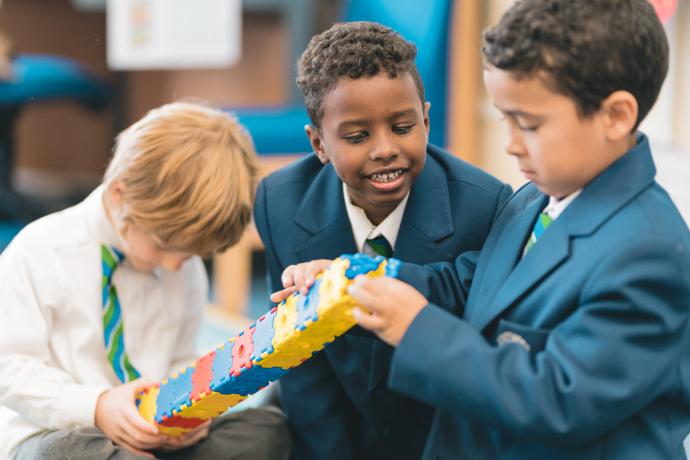 Image shows three primary aged schoolchildren building a Lego tower