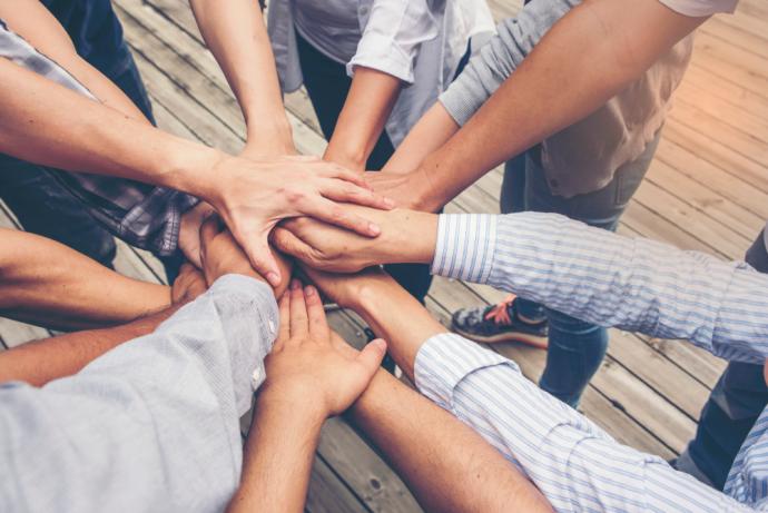 Group of people with their hands out in the middle of a circle