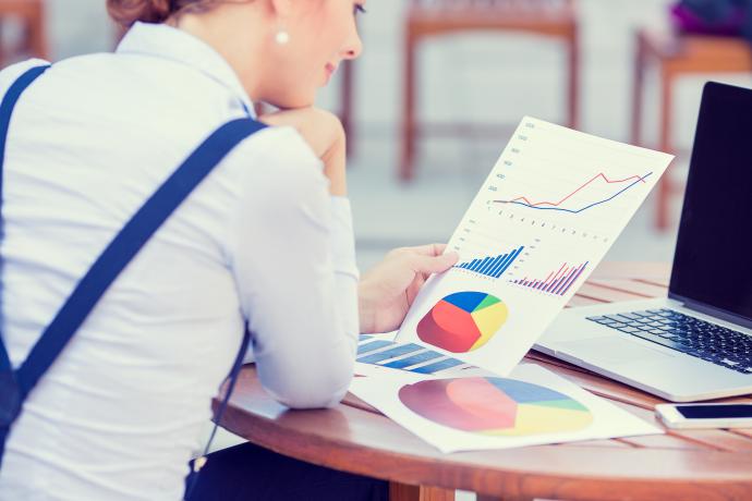 A person sat at a desk looking at graphs and charts on a piece of paper.