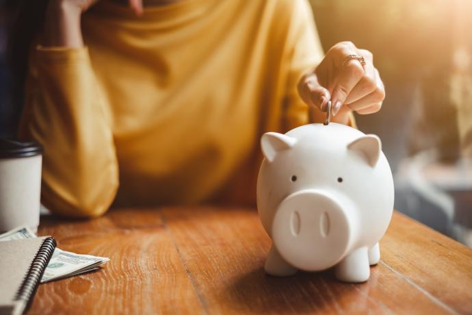 woman hand putting money coin into piggy bank for saving